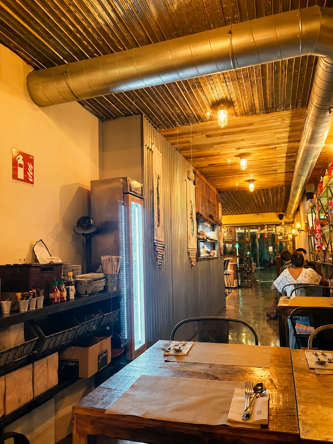 Warm dining corridor with drinks fridge and foreground table at THAI ISAAN