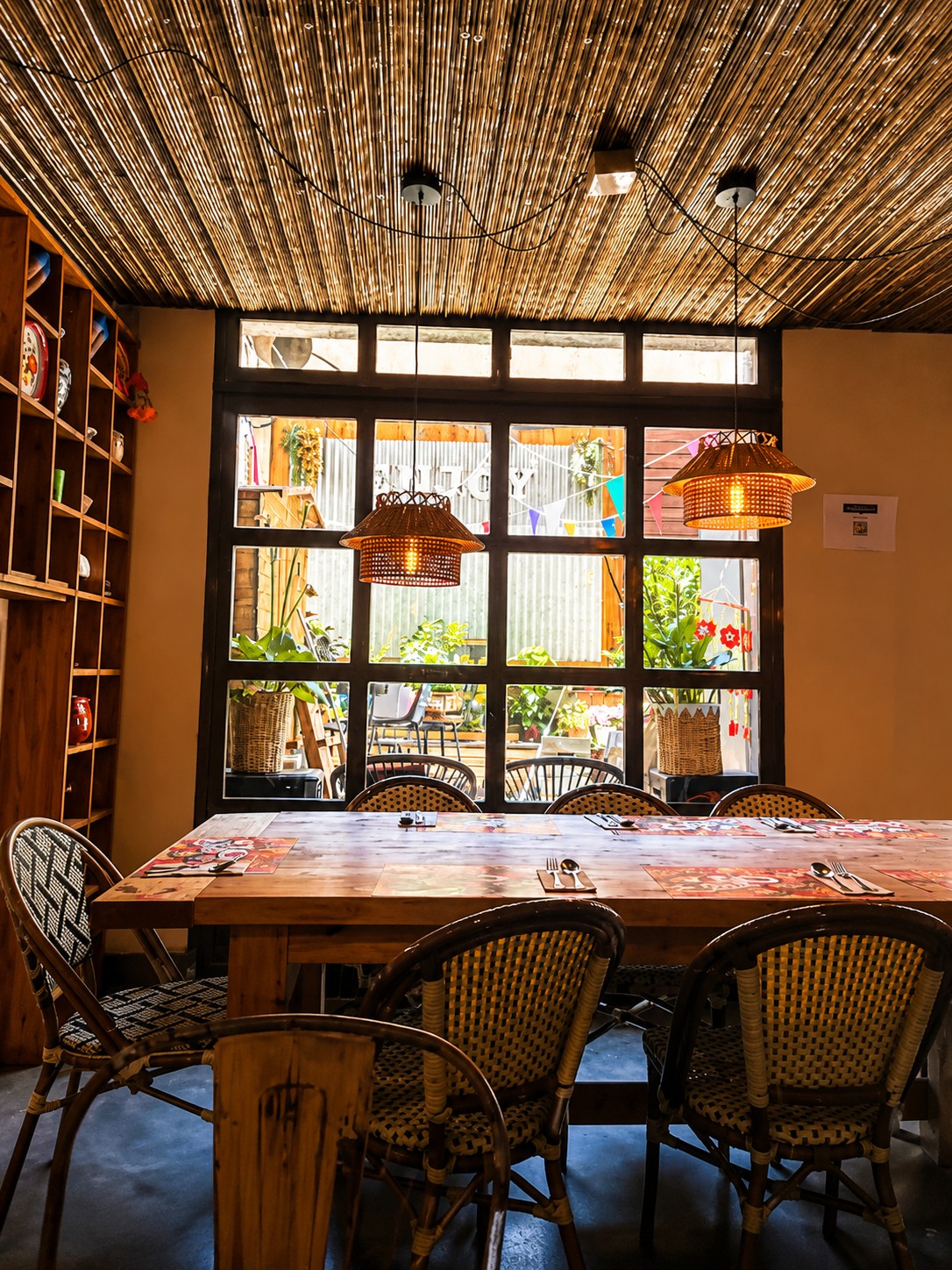 Communal table facing large windows under pendant lamps at THAI ISAAN